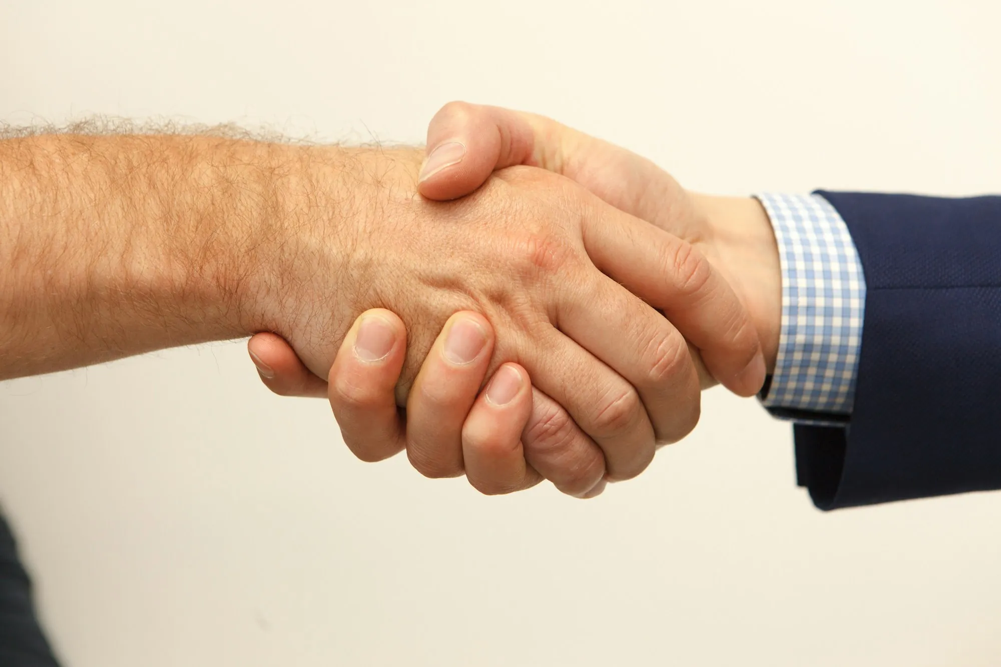 Close-up of two hands shaking against a light background